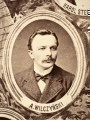Fotografie w odcieniu sepii umieszczone na tle drzew i roślin, w centralnym miejscu postać kobiety ze sztandarem i aniołkami, wkomponowane widoki budowanej stacji, mostu kolejowego i lokomotywy. Największe zdjęcie w górnej, środkowej części bez podpisu, prawdopodobnie inż. głównej kolei nadwiślańskiej Tadeusz Chrzanowski lub jego następca Walery Titkow. Wśród podobizn pracownicy Biura Głównego Inżyniera: inż. Włodzimierz Stanisławski - pomocnik głównego inżyniera; inż. Feliks Kucharzewski -  pomocnik naczelnika biura; Feliks Kamocki - naczelnik kancelarii; Witold Lanci - naczelnik Wydz. Architektury; dr Wacław Lasocki- służba zdrowia; Władysław Radwan - sprawy zakupu gruntów; inż. Stanisław hr Scipio - projektant mostów kolejowych i jego współpracownicy: inż. Stefan Zieliński, inż. Maurycy Machalski, inż. Feliks Kucharzewski. Fotografia w passe - partout, za szkłem, oprawiona w drewnianą, profilowaną ramę.