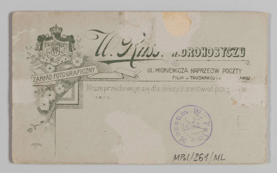 MPol/261/ML - Fotografia Jerzego Pola, wnuka Wincentego Pola, syna Marka Stanisława. Fotografia mężyczyzny w młodym wieku. Mężczyzna siedzi, jest lekko zwrócony w prawą stronę. Ubrany w ciemny garnitur, białą koszulę, na lewe ramię ma zarzucony czarny płaszcz. Lewa ręka położona na oparciu krzesła. Fotografia naklejona na kartonik, na którego odwrocie widnieje nadruk z wizytówką zakładu i jego filii, a pod spodem autograf właściciela atelier. 