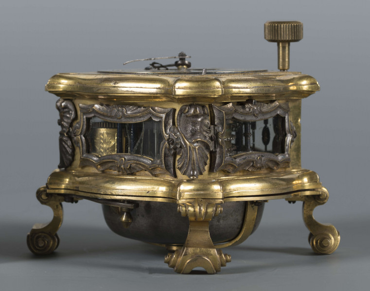 S/Mt/428/ML - Mechanizm o szkielecie płytowym, kwadratowym, łączonym balaskami. Wychwyt szpindlowy regulowany balansem włosowym; napęd sprężynowy chodu ze slimakiem wyrównawczym z funkcją bicia godzin i minut. Umieszczony w szkatule kwadratowej o falistych brzegach, na 4 nóżkach wolutowych; ścianki boczne oszklone w ozdobnie profilowanych ramkach, w narożach ornamenty muszlowo-wolutowe. W tarczy otwory naciągów przysłaniane, w narożniku wyłącznik biciawyłącznik bicia. Pierścień godzinowy srebrzony z rzymskimi oznaczeniemi godzin, arabskimi minut oraz kreskowa skala minutowa. Dwie proste wskazówki: godzinowa i minutowa. Na płycie dolnej mechanizmu obok koka, kółko regulacji chodu zegara: Avance Retard. Dwa młotki w formie muszli, dwie czasze zdwonków koncentrycznie umieszczone w klapie podstawy. 
Pośrodku tarczy dwie plakietki z dzieloną sygnaturą: 