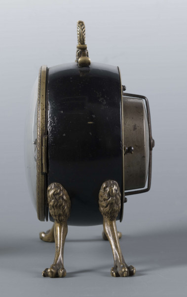 S/Mt/430/ML - Obudowa z brązu w formie bębna leżącego na czterech zwierzęcych łapach, pokrytego czarnym lakierem, z pionowym uchwytem w formie rozciągniętej profilowanej, wolutki. Tarcza zegarowa z mosiądzu, okrągła, moletowana mz malowanymi czarnymi cyframi rzymskimi godzin i oznaczeniem minut; dwie proste wskazówki; osłonieta zamykaną szybką o wypukłym profilu. Zamknięcie z tyłu w postaci okrągłych drzwiczek na zawiasie, z wmontowanym jednym dzwonkiem. Mechanizm mosiężny, o naciągu sprężynowym, z biciem godzin i kwadransów.
Na płycie wewnętrznej mechanizmu grawerowana sygnatura kursywą:
- Jacobus Staigier Lublin
