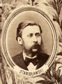 Fotografie w odcieniu sepii umieszczone na tle drzew i roślin, w centralnym miejscu postać kobiety ze sztandarem i aniołkami, wkomponowane widoki budowanej stacji, mostu kolejowego i lokomotywy. Największe zdjęcie w górnej, środkowej części bez podpisu, prawdopodobnie inż. głównej kolei nadwiślańskiej Tadeusz Chrzanowski lub jego następca Walery Titkow. Wśród podobizn pracownicy Biura Głównego Inżyniera: inż. Włodzimierz Stanisławski - pomocnik głównego inżyniera; inż. Feliks Kucharzewski -  pomocnik naczelnika biura; Feliks Kamocki - naczelnik kancelarii; Witold Lanci - naczelnik Wydz. Architektury; dr Wacław Lasocki- służba zdrowia; Władysław Radwan - sprawy zakupu gruntów; inż. Stanisław hr Scipio - projektant mostów kolejowych i jego współpracownicy: inż. Stefan Zieliński, inż. Maurycy Machalski, inż. Feliks Kucharzewski. Fotografia w passe - partout, za szkłem, oprawiona w drewnianą, profilowaną ramę.