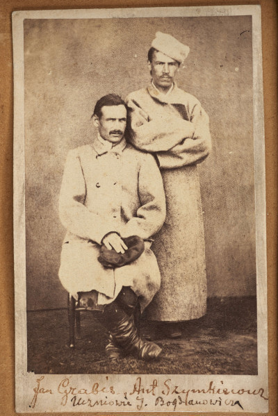 Tableau szklone zewnętrznie, w ramie, zawiera na tekturowym podłożu 15 fotografii uczestników powstania z terenu Wołynia. Pośrodku brak jednej, większej fotografii. Zdjęcia wykonane w sepii, w formacie pocztówkowym, niektóre z nich są podpisane pod spodem i na odwrociu: Eugeniusz Rdułtowski, Herkulan Kardussowski, F. Boryczewski, Antoni Straszewicz, Alfons Romanowski, Adam Hreczyna, Jan Grabis, Antoni Szymkiewicz.
Niektóre fotografie mają na kartonikach wyciskane napisy w języku rosyjskim. W środku tableau, pod pierwszym rzędem zdjęć przymocowany krzyżyk wykonany z chleba i tabaki, dekorowany motywem różyczek. Nad krzyżykiem druciana korona cierniowa, na niej krzyżyk z metalu z gałązką palmową. Niżej, pod brakującą fotografią lufka (?) z tektury, pierścionek i mały medalion ze Świętą Rodziną. Poniżej przymocowany grzebień rogowy, jakucki z napisem w języku rosyjskim i datą: 1864. Całość w ozdobnej ramie z dekoracyjnymi narożnikami, koroną, herbami Polski, Litwy, herbem z literą S. 