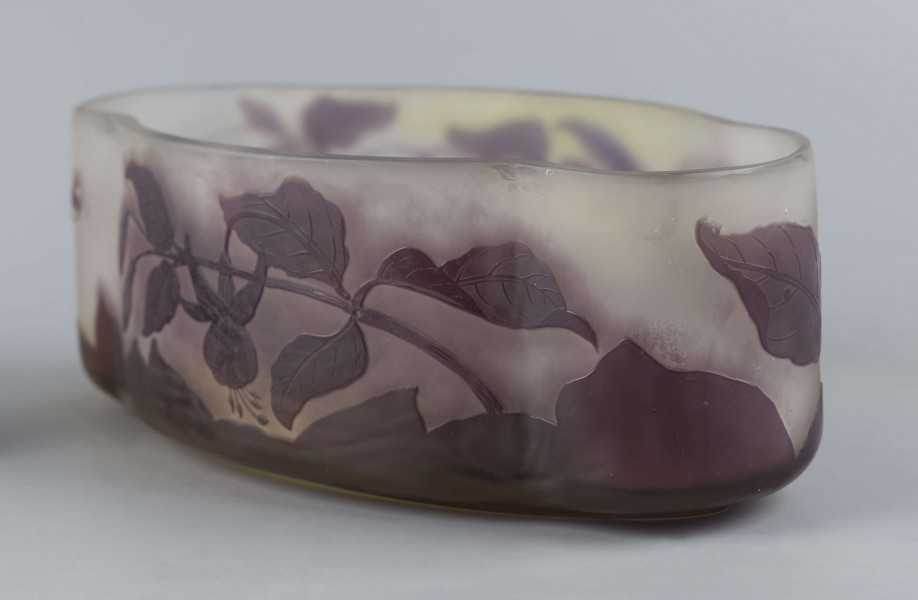 S/CS/1385/ML - Żardiniera ze szkła grubościennego, bezbarwnego, matowanego, podbarwianego żółtym i liliowym pudrem; na niskiej spiczasto-owalnej podstawie korpus o ściankach pionowo sfalowanych, u dołu lekko zaokrąglony, górna krawędź ścięta. Korpus pokryty warstwą liliową, w niej trawiony wzór roslinny: gałązka fuksji z kwiatami, przy dnie dookoła  pasmo liliowe o nieregularnym wykroju.
 