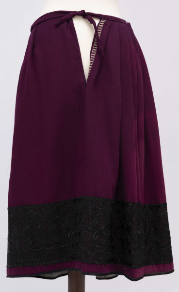 E/11633/ML - Spódnica z wełenki ciemnofioletowej, wszyta w pasek. Zszyta z 4 brytów. Wykończona czarną szczoteczką, powyżej pas (szer. 17 cm) tiulowej czarnej koronki o stylizowanym ornamencie roślinnym.