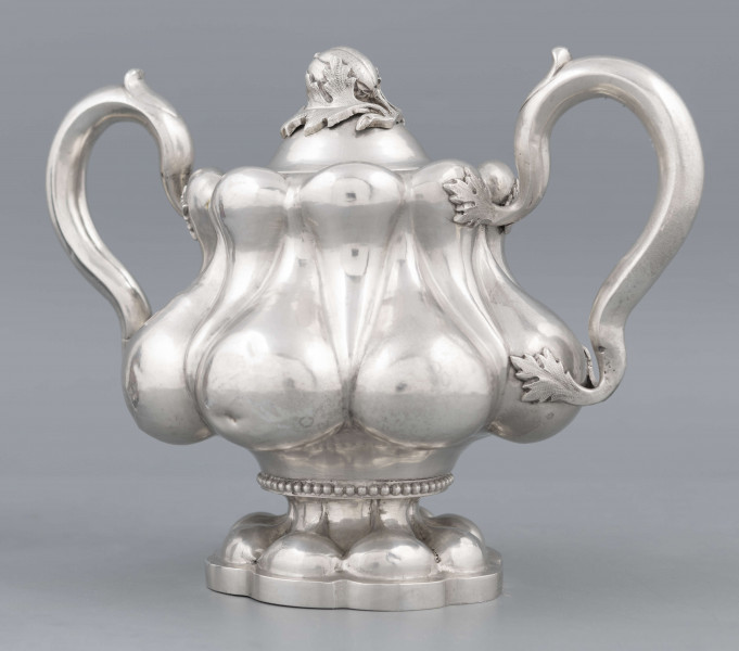 S/Mt/392/ML - Stopa ośmiolistna z ośmioma wydatnymi puklami; trzon krótki zdobiony rzedem perełek; korpus gruszkowaty pokryty dwoma rzędami pukli w formie kropel - większe na dole, mniejsze u góry; po bokach dwa ucha w formie litery 