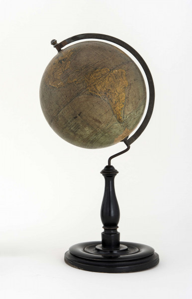 Globus bez tytułu, roku wydania i granic państwowych. Brak hipsometrii, powierzchnia kontynentów jest bladożółta za wyjątkiem białej Antarktydy. Na lądach naniesiono rzeki, pustynie i jeziora zaznaczono szrafurą. Największe góry oznaczono metodą kreskową (za pomocą 