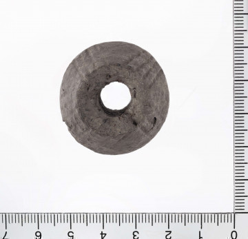 1624/A/ML/3 - Przęślik o formie dwustożkowatej w przekroju został wylepiony ręcznie z gliny i wypalony na kolor jasnobrązowy. Powierzchnie przy otworach są płasko ścięte. Na zewnętrznych ściankach obydwu stożków występują motywy ryte w postaci pasa pionowych i ukośnych kresek pogrupowanych w zespoły od dwóch do ośmiu nacięć. Na drugim pasie ornamentu nacięcia układają się w formę krzyża lub kwiatka. 