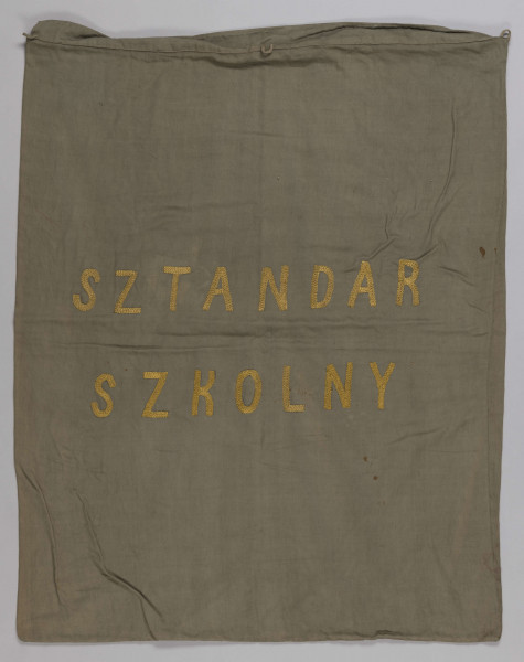 ML/H/200 - Sztandar Przedszkola i Seminarium Ochroniarskiego Marii Papiewskiej. Sztandar w formie kwadratu zszytego z dwóch kawałków ozdobnej tkaniny, obszyty frędzlami. Wzdłuż jednej z krawędzi mocowania w formie troczków do zaczepienia na drzewcu. Na awersie pośrodku tkaniny w kremowym kolorze w kwiatowe motywy herb miasta Lublina (koziołek wsparty o winną latorośl umieszczony na czerwonym polu na tarczy zwieńczonej koroną) oraz haftowany w półkolu czerwoną nicią napis z nazwą posiadacza. Na rewersie pośrodku wzorzystej tkaniny w kolorze czerwonym haftowany biały orzeł w złotej koronie wysadzanej klejnotami z umieszczoną poniżej haftowaną w kolorze złotym datą 1916 r. Metalowa głowica w kształcie orła w koronie umocowanego na kuli. Dodatkowo materiałowy pokrowiec zapinany u góry na napy i haftki, w kolorze zielonkawym, z wyhaftowanym pośrodku napisem w kolorze żółtym.