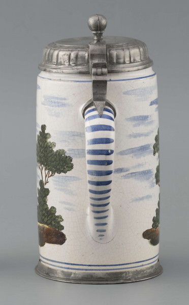 S/CS/64/ML - Korpus cylindryczny z uchem w kształcie litery „C”, pokrywka cynowa, płaska z profilowanym brzegiem i kulistą sterczyną  na zawiasie umocowanym do ucha; profilowana cynowa obręcz otacza dolną krawędź. Pokryty białym szkliwem z wielobarwną dekoracją malowaną skomponowaną przeciwlegle do ucha. Przedstawia ona w uproszczony sposób scenę w obozie  wojskowym: dwaj uzbrojeni kosynierzy stoją na wprost siebie, za nimi widoczny namiot a wokół zielone zarośla i drzewa. Niebo zaznaczone błękitnymi plamami, w tym samym kolorze malowane paski obiegają krawędzie naczynia i zdobią ucho. Tematyka przedstawienia ma wyraźnie patriotyczny charakter nawiązując do powstania kościuszkowskiego.

