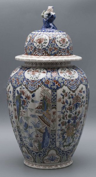 S/CS/546/ML - Wazon owoidalny o niskiej podstawie i niskiej pierścieniowej szyi, powierzchnia drobno kanelowana, pokrywa kopulasta z szerokim kołnierzem, uchwyt w kształcie lwa Fo wspartego prawą łapą na pniu drzewa (?). Dekoracja malowana podszkliwnie w kolorach błękitu, czerwieni, zieleni, żółcieni. W sześciu owalnych, wydłużonych rezerwach na przemian kompozycja kwiatowa z peonią i pejzaż nadrzeczny z architekturą o charakterze orientalnym. U góry - na barkach - sześć owalnych rezerw z kwitnącą gałązką, na dole sześć rezerw trójlistnych z motywem uproszczonej muszli i wolut, na stopie fryz wolutowy, na szyi wąska ukośna kratka. Na pokrywie powtórzona dekoracja z barków, kołnierz biały z fryzem wolutowym analogicznie jak na stopie.
 