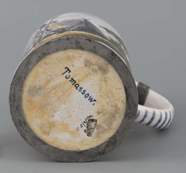 S/CS/64/ML - Korpus cylindryczny z uchem w kształcie litery „C”, pokrywka cynowa, płaska z profilowanym brzegiem i kulistą sterczyną  na zawiasie umocowanym do ucha; profilowana cynowa obręcz otacza dolną krawędź. Pokryty białym szkliwem z wielobarwną dekoracją malowaną skomponowaną przeciwlegle do ucha. Przedstawia ona w uproszczony sposób scenę w obozie  wojskowym: dwaj uzbrojeni kosynierzy stoją na wprost siebie, za nimi widoczny namiot a wokół zielone zarośla i drzewa. Niebo zaznaczone błękitnymi plamami, w tym samym kolorze malowane paski obiegają krawędzie naczynia i zdobią ucho. Tematyka przedstawienia ma wyraźnie patriotyczny charakter nawiązując do powstania kościuszkowskiego.

