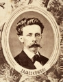 Fotografie w odcieniu sepii umieszczone na tle drzew i roślin, w centralnym miejscu postać kobiety ze sztandarem i aniołkami, wkomponowane widoki budowanej stacji, mostu kolejowego i lokomotywy. Największe zdjęcie w górnej, środkowej części bez podpisu, prawdopodobnie inż. głównej kolei nadwiślańskiej Tadeusz Chrzanowski lub jego następca Walery Titkow. Wśród podobizn pracownicy Biura Głównego Inżyniera: inż. Włodzimierz Stanisławski - pomocnik głównego inżyniera; inż. Feliks Kucharzewski -  pomocnik naczelnika biura; Feliks Kamocki - naczelnik kancelarii; Witold Lanci - naczelnik Wydz. Architektury; dr Wacław Lasocki- służba zdrowia; Władysław Radwan - sprawy zakupu gruntów; inż. Stanisław hr Scipio - projektant mostów kolejowych i jego współpracownicy: inż. Stefan Zieliński, inż. Maurycy Machalski, inż. Feliks Kucharzewski. Fotografia w passe - partout, za szkłem, oprawiona w drewnianą, profilowaną ramę.