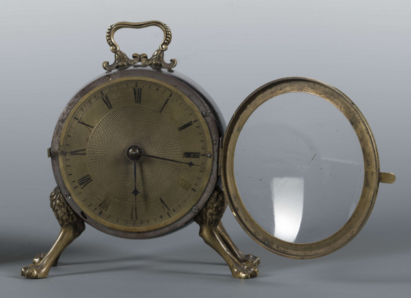 S/Mt/430/ML - Obudowa z brązu w formie bębna leżącego na czterech zwierzęcych łapach, pokrytego czarnym lakierem, z pionowym uchwytem w formie rozciągniętej profilowanej, wolutki. Tarcza zegarowa z mosiądzu, okrągła, moletowana mz malowanymi czarnymi cyframi rzymskimi godzin i oznaczeniem minut; dwie proste wskazówki; osłonieta zamykaną szybką o wypukłym profilu. Zamknięcie z tyłu w postaci okrągłych drzwiczek na zawiasie, z wmontowanym jednym dzwonkiem. Mechanizm mosiężny, o naciągu sprężynowym, z biciem godzin i kwadransów.
Na płycie wewnętrznej mechanizmu grawerowana sygnatura kursywą:
- Jacobus Staigier Lublin
