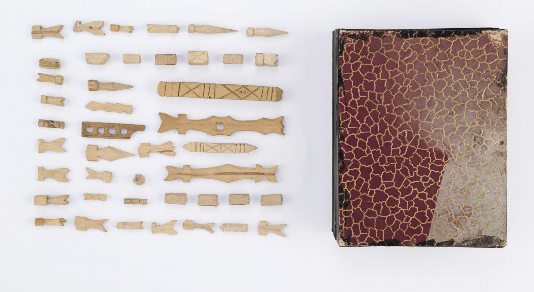 Figurki gry dziecięcej służące do zabawy z podrzucaniem. Wystrugane z drewna w formie płaskich abstrakcyjnych kształtów. Składała się z 57 elementów różnego kształtu i wielkości. Obecnie 43 szt.