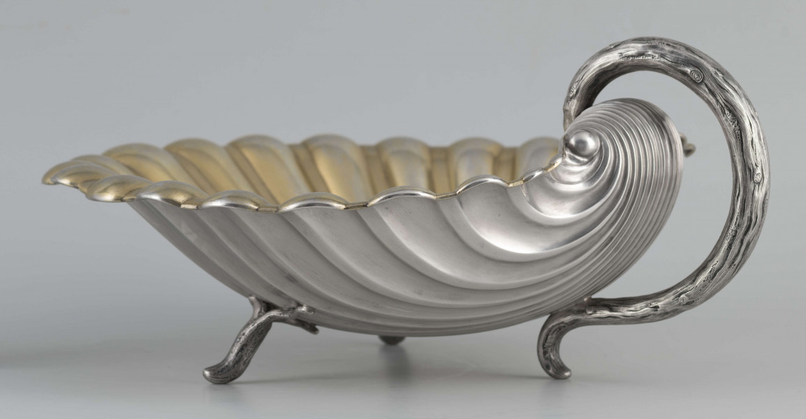 S/Mt/504/ML - Patera z uchwytem, w formie muszli przegrzebka ustawionej poziomo na  dwóch nóżkach - trzecią nóżkę tworzy zakończenie pionowo umocowanego esowatego ucha. 
Na odwrocie sygnatura segmentowa:
- znak miejski Petersburga
- znak imienny złotnika  