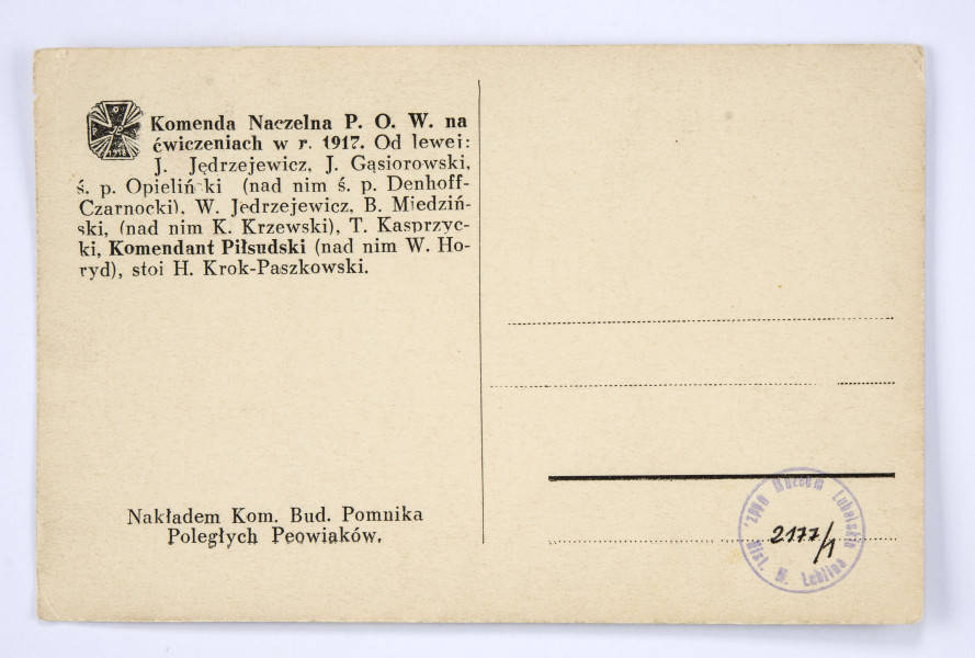 Pocztówka sepiowana - Komenda Naczelna Polskiej Organizacji Wojskowej na ćwiczeniach w 1917 r. (zdjęcie grupowe w plenerze). Ujęcie w poziomie.
AWERS: grupa mężczyzn (11 osób) w mundurach austriackich lub ubraniach cywilnych; wśród nich komendant Józef Piłsudski; zdjęcie wykonane w lesie.
REWERS: czarna linatura z miejscem na korespondencje; w l. g. rogu nadruk w postaci odznaki pamiątkowej 
