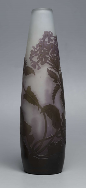 S/CS/1620/ML - Wazon o kształcie wrzecionowatym ze szkła grubościennego, matowego, bezbarwnego,  podbarwionego od dołu fioletem, od góry błękitem. Powlekany warstwą liliową i brązowooliwkową; w niej trawiona i polerowana dekoracja roślinna: swobodnie rozmieszczone gałązki werbeny z kwiatami.
 