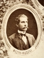 Fotografie w odcieniu sepii umieszczone na tle drzew i roślin, w centralnym miejscu postać kobiety ze sztandarem i aniołkami, wkomponowane widoki budowanej stacji, mostu kolejowego i lokomotywy. Największe zdjęcie w górnej, środkowej części bez podpisu, prawdopodobnie inż. głównej kolei nadwiślańskiej Tadeusz Chrzanowski lub jego następca Walery Titkow. Wśród podobizn pracownicy Biura Głównego Inżyniera: inż. Włodzimierz Stanisławski - pomocnik głównego inżyniera; inż. Feliks Kucharzewski -  pomocnik naczelnika biura; Feliks Kamocki - naczelnik kancelarii; Witold Lanci - naczelnik Wydz. Architektury; dr Wacław Lasocki- służba zdrowia; Władysław Radwan - sprawy zakupu gruntów; inż. Stanisław hr Scipio - projektant mostów kolejowych i jego współpracownicy: inż. Stefan Zieliński, inż. Maurycy Machalski, inż. Feliks Kucharzewski. Fotografia w passe - partout, za szkłem, oprawiona w drewnianą, profilowaną ramę.