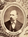 Fotografie w odcieniu sepii umieszczone na tle drzew i roślin, w centralnym miejscu postać kobiety ze sztandarem i aniołkami, wkomponowane widoki budowanej stacji, mostu kolejowego i lokomotywy. Największe zdjęcie w górnej, środkowej części bez podpisu, prawdopodobnie inż. głównej kolei nadwiślańskiej Tadeusz Chrzanowski lub jego następca Walery Titkow. Wśród podobizn pracownicy Biura Głównego Inżyniera: inż. Włodzimierz Stanisławski - pomocnik głównego inżyniera; inż. Feliks Kucharzewski -  pomocnik naczelnika biura; Feliks Kamocki - naczelnik kancelarii; Witold Lanci - naczelnik Wydz. Architektury; dr Wacław Lasocki- służba zdrowia; Władysław Radwan - sprawy zakupu gruntów; inż. Stanisław hr Scipio - projektant mostów kolejowych i jego współpracownicy: inż. Stefan Zieliński, inż. Maurycy Machalski, inż. Feliks Kucharzewski. Fotografia w passe - partout, za szkłem, oprawiona w drewnianą, profilowaną ramę.