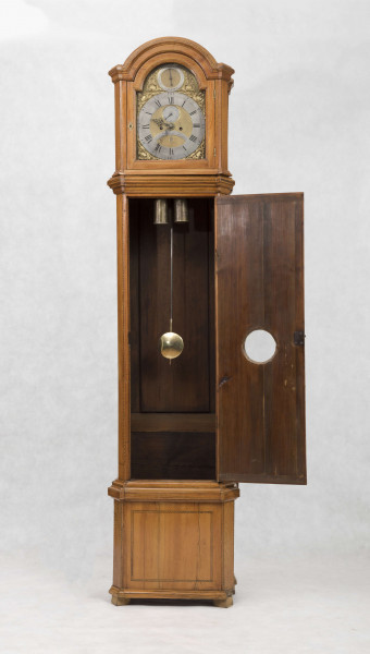 Tarcza w kształcie kwadratu zwieńczonego półkolem, złocona, w narożach ornamenty odlewane z brązu, złocone; pierścień  godzinowy srebrzony z rzymskimi oznaczeniami godzin i zaznaczonymi minutami, wewnątrz tarcza sekundnika, tarczka budzika, plakietka z sygnaturą 