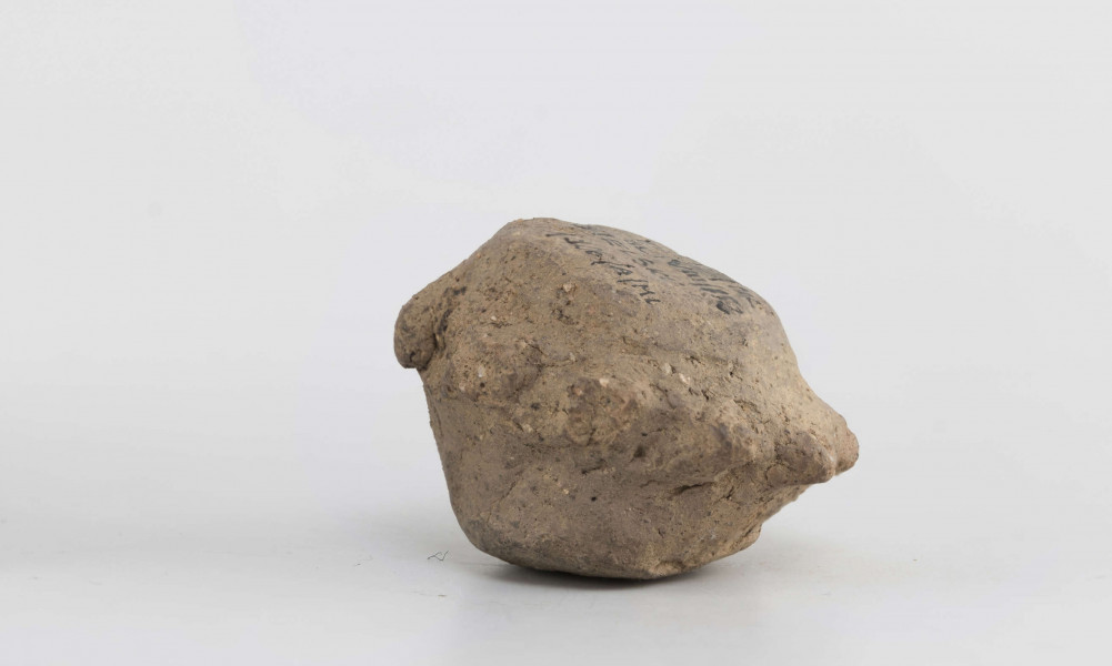 Grzechotka gliniana. Kształt zbliżony do walcowatego. W połowie wysokości ozdobiona 9 guzkami.