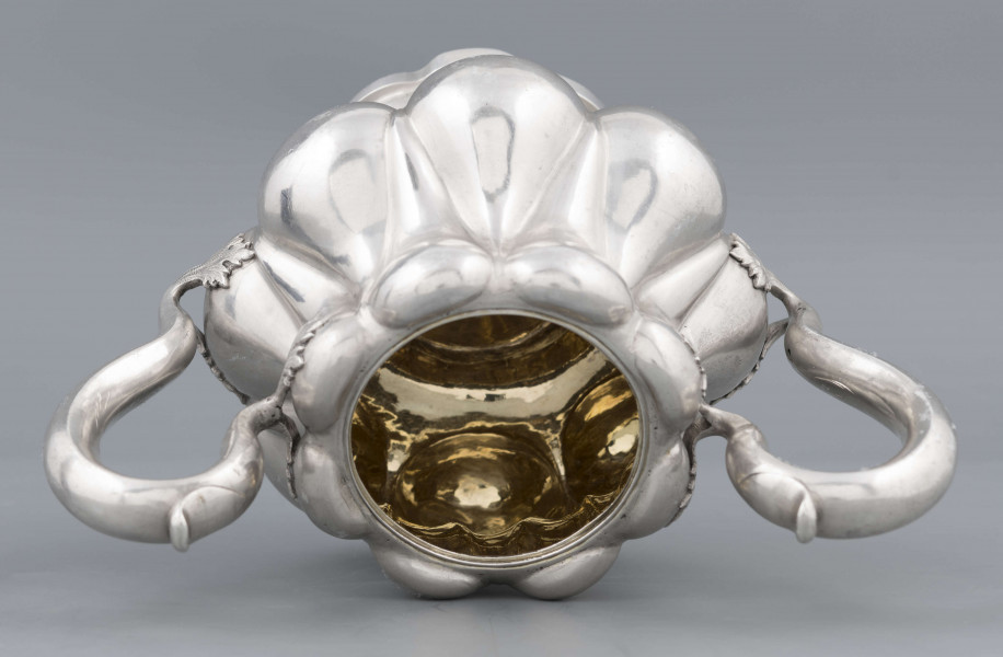 S/Mt/392/ML - Stopa ośmiolistna z ośmioma wydatnymi puklami; trzon krótki zdobiony rzedem perełek; korpus gruszkowaty pokryty dwoma rzędami pukli w formie kropel - większe na dole, mniejsze u góry; po bokach dwa ucha w formie litery 