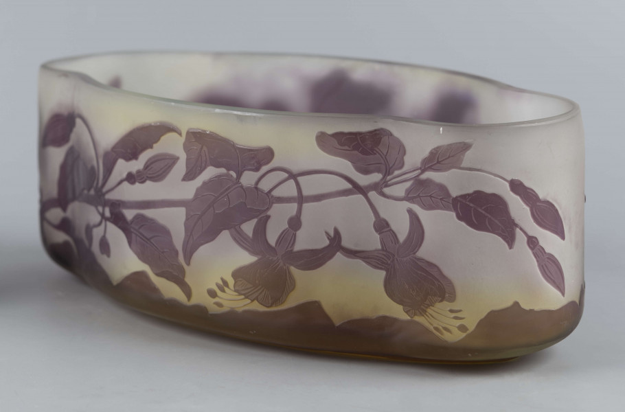 S/CS/1385/ML - Żardiniera ze szkła grubościennego, bezbarwnego, matowanego, podbarwianego żółtym i liliowym pudrem; na niskiej spiczasto-owalnej podstawie korpus o ściankach pionowo sfalowanych, u dołu lekko zaokrąglony, górna krawędź ścięta. Korpus pokryty warstwą liliową, w niej trawiony wzór roslinny: gałązka fuksji z kwiatami, przy dnie dookoła  pasmo liliowe o nieregularnym wykroju.
 