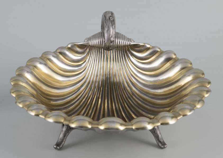 S/Mt/504/ML - Patera z uchwytem, w formie muszli przegrzebka ustawionej poziomo na  dwóch nóżkach - trzecią nóżkę tworzy zakończenie pionowo umocowanego esowatego ucha. 
Na odwrocie sygnatura segmentowa:
- znak miejski Petersburga
- znak imienny złotnika  