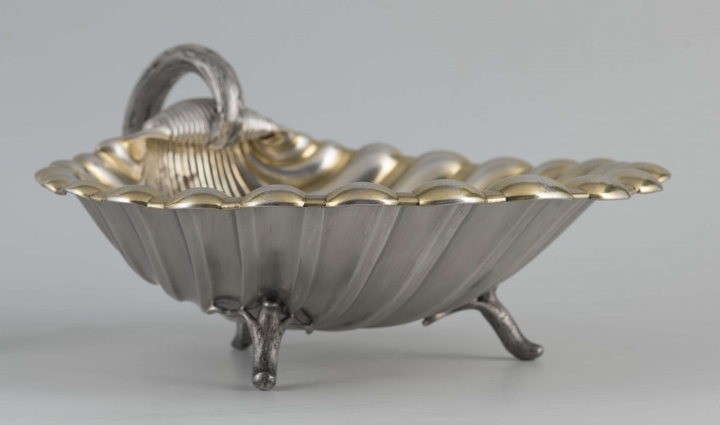 S/Mt/504/ML - Patera z uchwytem, w formie muszli przegrzebka ustawionej poziomo na  dwóch nóżkach - trzecią nóżkę tworzy zakończenie pionowo umocowanego esowatego ucha. 
Na odwrocie sygnatura segmentowa:
- znak miejski Petersburga
- znak imienny złotnika  