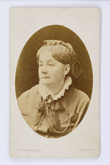 Fotografia przedstawia popiersie kobiety w średnim wieku. Kobieta ma na głowie stroik, włosy zaczesane do tyłu, przy sukni ozdobny kołnierzyk. Głowa odwrócona 3/4 w lewo. Fotografia w owalu, naklejona na biały kartonik. U dołu napis: W. Twardzicki, Varsovie. Fotografia siostry Wincentego Pola, Wiktorii Longchamps de Berier. Na odwrocie znak firmowy i podpisy wykonane nieznaną ręką.
