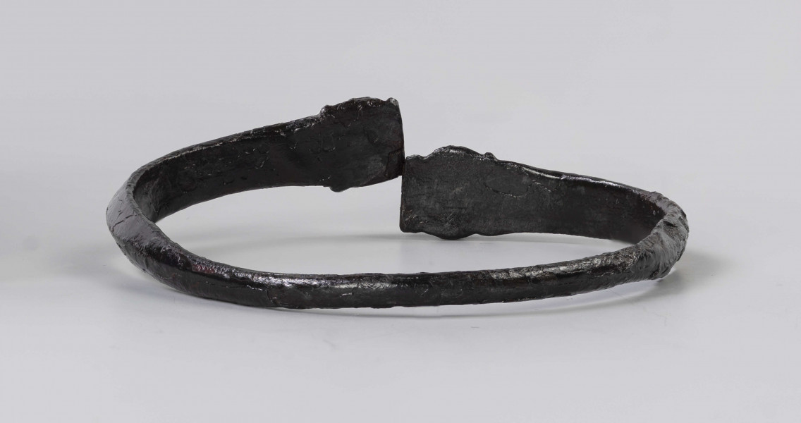 824/A/ML/1 - Żelazna bransoleta ze stylizowanymi wężowymi główkami. W części środkowej przekrój trapezowaty, przy główkach trójkątny.