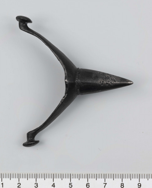 1044/A/ML/1 - Ostroga żelazna z wklęsłym do wewnątrz, łukowatym kabłąkiem. Szeroki przy nasadzie kolca kabłąk zwęża sie stopniowo, przechodząc w wałkowate wygięcia zaczepu, zakończone soczewkowatymi guzkami. Kolec częściowo pusty, ma kształt przegiętego nieznacznie, facetowanego stożka. Przy nasadzie dwie wypiłowane bruzdy z gęsto poprzecznie nacinanym grzbietem powstałym między nimi. Ostroga stanowi element wyposażenia ciałopalnego pochówku złożonego prawdopodobnie w popielnicy. Odkrycia dokonano w 1959 roku przypadkowo w czasie prac rolnych. Oprócz trzech grotów, pochówkowi wojownika towarzyszyły: żelazne umbo, dwie ostrogi, tok brązowy (prawdopodobnie okucie drzewca oszczepu) a także żelazny miecz z miedziana inkrustacją wyobrażającą rzymskich bogów. Pochowany na terenie obecnej wsi Podlodów wojownik należał do elity wojskowej przedstawicieli kultury przeworskiej.
Wymiary dodatkowe: 1,6 cm (podstawa kolca); 1,0 cm (śr. guzków); 3,2 cm (szer. kabłąka przy nasadzie kolca); 0,5 cm (szer. kabłaka przy zaczepach)