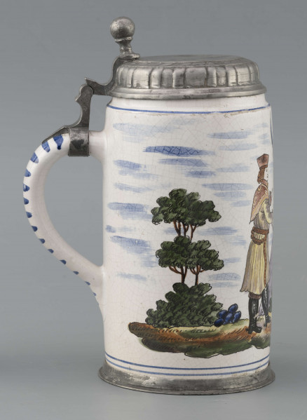 S/CS/64/ML - Korpus cylindryczny z uchem w kształcie litery „C”, pokrywka cynowa, płaska z profilowanym brzegiem i kulistą sterczyną  na zawiasie umocowanym do ucha; profilowana cynowa obręcz otacza dolną krawędź. Pokryty białym szkliwem z wielobarwną dekoracją malowaną skomponowaną przeciwlegle do ucha. Przedstawia ona w uproszczony sposób scenę w obozie  wojskowym: dwaj uzbrojeni kosynierzy stoją na wprost siebie, za nimi widoczny namiot a wokół zielone zarośla i drzewa. Niebo zaznaczone błękitnymi plamami, w tym samym kolorze malowane paski obiegają krawędzie naczynia i zdobią ucho. Tematyka przedstawienia ma wyraźnie patriotyczny charakter nawiązując do powstania kościuszkowskiego.

