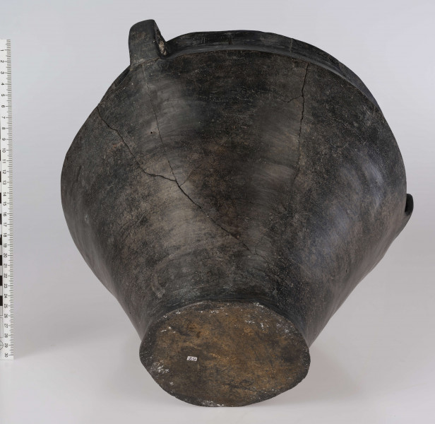 765/A/ML/1 - Waza wyraźnie profilowana, z prostym, odgietym na zewnatrz brzegiem, ostro zaznaczonym załomem brzuśca i wyodrębnionym dnem. Ponad załomem brzuśca występuje ornament w postaci: jodełek, swastyk, tworzonych przez dwie linie ryte i rząd dołków pomiędzy nimi oraz ornament blankowy. Naczynie ma trzy taśmowate ucha kolankowato zgięte. 
