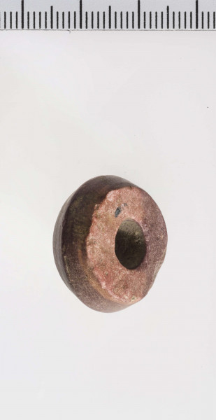 wykonany z łupka owruckiego; dwustożkowy, ostro profilowany; linia tworząca kształt dwustożkowy biegnie nieregularnie na różnych wysokościach; płasko ścięty przy otworze; otwór średniej wielkości, cylindryczny