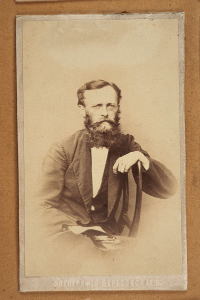 Tableau szklone zewnętrznie, w ramie, zawiera na tekturowym podłożu 15 fotografii uczestników powstania z terenu Wołynia. Pośrodku brak jednej, większej fotografii. Zdjęcia wykonane w sepii, w formacie pocztówkowym, niektóre z nich są podpisane pod spodem i na odwrociu: Eugeniusz Rdułtowski, Herkulan Kardussowski, F. Boryczewski, Antoni Straszewicz, Alfons Romanowski, Adam Hreczyna, Jan Grabis, Antoni Szymkiewicz.
Niektóre fotografie mają na kartonikach wyciskane napisy w języku rosyjskim. W środku tableau, pod pierwszym rzędem zdjęć przymocowany krzyżyk wykonany z chleba i tabaki, dekorowany motywem różyczek. Nad krzyżykiem druciana korona cierniowa, na niej krzyżyk z metalu z gałązką palmową. Niżej, pod brakującą fotografią lufka (?) z tektury, pierścionek i mały medalion ze Świętą Rodziną. Poniżej przymocowany grzebień rogowy, jakucki z napisem w języku rosyjskim i datą: 1864. Całość w ozdobnej ramie z dekoracyjnymi narożnikami, koroną, herbami Polski, Litwy, herbem z literą S. 