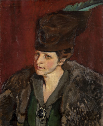 Portret kobiecy, w popiersiu, w ujęciu 3/4. Ubrana w szaro - zieloną suknię z długim kołnierzem, spiętym na piersi dużą broszką z czarnym kamieniem. Na ramionach ciemnoszare futro. Na głowie kapelusz ozdobiony zielonym piórem. Twarz o jasnej karnacji, z ostro zarysowanym podbródkiem, nos długi, niewielkie oczy. Włosy ciemne, schowane pod kapeluszem. Tło neutralne czerwono-brązowe.