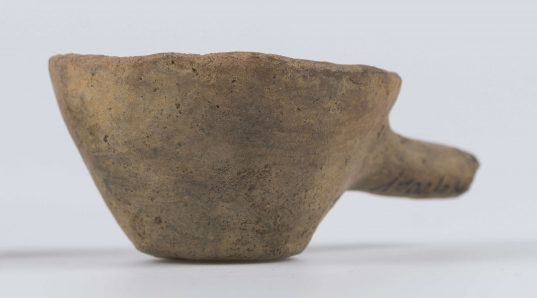 1702/A/ML - dno płaskie, ścianki proste, wylew zawinięty do wewnątrz; krawędź zaokrąglona; pod krawędzią umieszczono trzymadełko prostopadłe do ścianki, o przekroju owalnym, ułamane