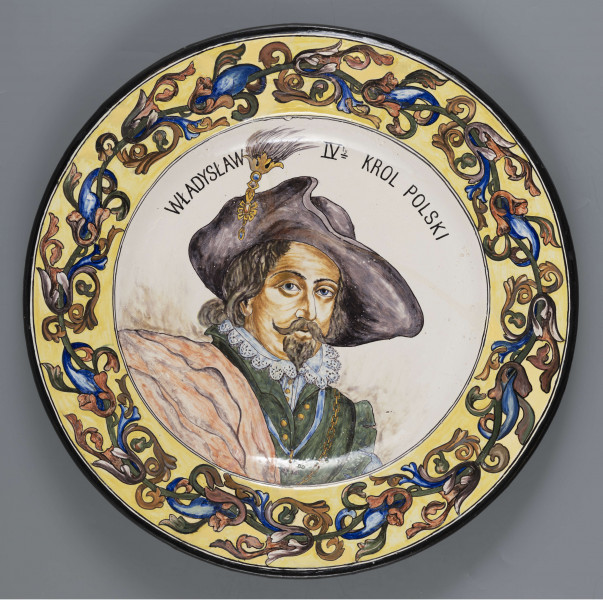 S/CS/1215/ML - Pólmisek pokrągły, gładki, szkliwiony, dekoracja malowana wielobarwnie. W lustrze malowane wielobarwnie popiersie portretowe Władysława IV zwróconego 3/4 w prawo. Wizerunek króla wzorowany na portrecie pedzla P.P. Rubesa; nad głową półkoliście biegnący napis majuskułą w kolorze czarnym: WŁADYSŁAW IV KROL POLSKI. Kołnierz pokryty stylizowanym fryzem liściasto-wolutowym w odcieniach cynobru, błękitu i zieleni na żółtym tle. Krawędź obwiedziona ciemnogranatowym konturem.
