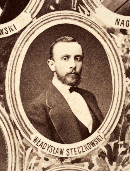 Fotografie w odcieniu sepii umieszczone na tle drzew i roślin, w centralnym miejscu postać kobiety ze sztandarem i aniołkami, wkomponowane widoki budowanej stacji, mostu kolejowego i lokomotywy. Największe zdjęcie w górnej, środkowej części bez podpisu, prawdopodobnie inż. głównej kolei nadwiślańskiej Tadeusz Chrzanowski lub jego następca Walery Titkow. Wśród podobizn pracownicy Biura Głównego Inżyniera: inż. Włodzimierz Stanisławski - pomocnik głównego inżyniera; inż. Feliks Kucharzewski -  pomocnik naczelnika biura; Feliks Kamocki - naczelnik kancelarii; Witold Lanci - naczelnik Wydz. Architektury; dr Wacław Lasocki- służba zdrowia; Władysław Radwan - sprawy zakupu gruntów; inż. Stanisław hr Scipio - projektant mostów kolejowych i jego współpracownicy: inż. Stefan Zieliński, inż. Maurycy Machalski, inż. Feliks Kucharzewski. Fotografia w passe - partout, za szkłem, oprawiona w drewnianą, profilowaną ramę.