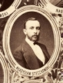 Fotografie w odcieniu sepii umieszczone na tle drzew i roślin, w centralnym miejscu postać kobiety ze sztandarem i aniołkami, wkomponowane widoki budowanej stacji, mostu kolejowego i lokomotywy. Największe zdjęcie w górnej, środkowej części bez podpisu, prawdopodobnie inż. głównej kolei nadwiślańskiej Tadeusz Chrzanowski lub jego następca Walery Titkow. Wśród podobizn pracownicy Biura Głównego Inżyniera: inż. Włodzimierz Stanisławski - pomocnik głównego inżyniera; inż. Feliks Kucharzewski -  pomocnik naczelnika biura; Feliks Kamocki - naczelnik kancelarii; Witold Lanci - naczelnik Wydz. Architektury; dr Wacław Lasocki- służba zdrowia; Władysław Radwan - sprawy zakupu gruntów; inż. Stanisław hr Scipio - projektant mostów kolejowych i jego współpracownicy: inż. Stefan Zieliński, inż. Maurycy Machalski, inż. Feliks Kucharzewski. Fotografia w passe - partout, za szkłem, oprawiona w drewnianą, profilowaną ramę.