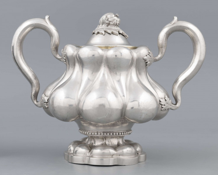 S/Mt/392/ML - Stopa ośmiolistna z ośmioma wydatnymi puklami; trzon krótki zdobiony rzedem perełek; korpus gruszkowaty pokryty dwoma rzędami pukli w formie kropel - większe na dole, mniejsze u góry; po bokach dwa ucha w formie litery 