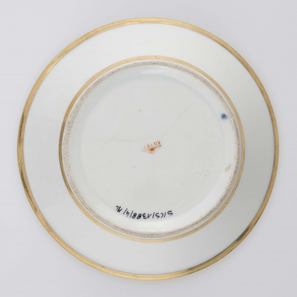 S/CS/1388/4/ML - Spodek koniczny, na kołnierzu dekoracja malowana wielobarwnie i złocona: szeroki fryz złożony ze stylizowanych ornamentów roślinnych (gałązek, kłosów zbóż i liści akantu)  połączonych z owalnymi medalionami, w których są trzy różowe różyczki z zielonymi listkami na złotym tle. Pośrodku lustra złote kółko, wylew złocony  od  spodu krawędzie obwiedzione złotym konturem.  

