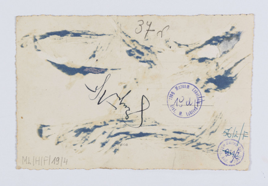 ML/H/F/19/4 - Do fotografii pozuje grupa kilkunastu dziewcząt wraz z ich opiekunką stojącą na skraju grupy po lewej stronie oraz mężczyną w kapeluszu pośrodku. Dziewczęta ubrane są w płaszcze, część ma nakrycia głowy - berety. Stoją na chodniku przed dużą witryną sklepu. Nad wejściem umieszczony duży szydl złożony z białych liter: LOPP. 