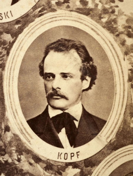 Fotografie w odcieniu sepii umieszczone na tle drzew i roślin, w centralnym miejscu postać kobiety ze sztandarem i aniołkami, wkomponowane widoki budowanej stacji, mostu kolejowego i lokomotywy. Największe zdjęcie w górnej, środkowej części bez podpisu, prawdopodobnie inż. głównej kolei nadwiślańskiej Tadeusz Chrzanowski lub jego następca Walery Titkow. Wśród podobizn pracownicy Biura Głównego Inżyniera: inż. Włodzimierz Stanisławski - pomocnik głównego inżyniera; inż. Feliks Kucharzewski -  pomocnik naczelnika biura; Feliks Kamocki - naczelnik kancelarii; Witold Lanci - naczelnik Wydz. Architektury; dr Wacław Lasocki- służba zdrowia; Władysław Radwan - sprawy zakupu gruntów; inż. Stanisław hr Scipio - projektant mostów kolejowych i jego współpracownicy: inż. Stefan Zieliński, inż. Maurycy Machalski, inż. Feliks Kucharzewski. Fotografia w passe - partout, za szkłem, oprawiona w drewnianą, profilowaną ramę.