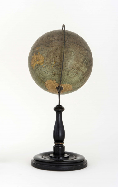 Globus bez tytułu, roku wydania i granic państwowych. Brak hipsometrii, powierzchnia kontynentów jest bladożółta za wyjątkiem białej Antarktydy. Na lądach naniesiono rzeki, pustynie i jeziora zaznaczono szrafurą. Największe góry oznaczono metodą kreskową (za pomocą 