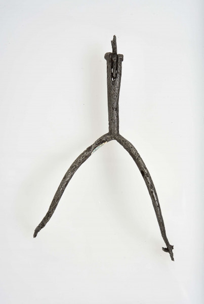 Ostroga żelazna w kształcie wideł z półkoliście wygiętymi ramionami zakaończonymi gwiazdkami; kolec również zakończony gwiazdką umocowaną przez włożenie jej w rozszczepiony kolec i przewleczono nitem