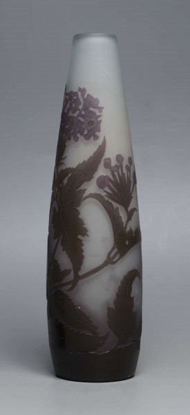 S/CS/1620/ML - Wazon o kształcie wrzecionowatym ze szkła grubościennego, matowego, bezbarwnego,  podbarwionego od dołu fioletem, od góry błękitem. Powlekany warstwą liliową i brązowooliwkową; w niej trawiona i polerowana dekoracja roślinna: swobodnie rozmieszczone gałązki werbeny z kwiatami.
 