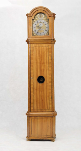 Tarcza w kształcie kwadratu zwieńczonego półkolem, złocona, w narożach ornamenty odlewane z brązu, złocone; pierścień  godzinowy srebrzony z rzymskimi oznaczeniami godzin i zaznaczonymi minutami, wewnątrz tarcza sekundnika, tarczka budzika, plakietka z sygnaturą 