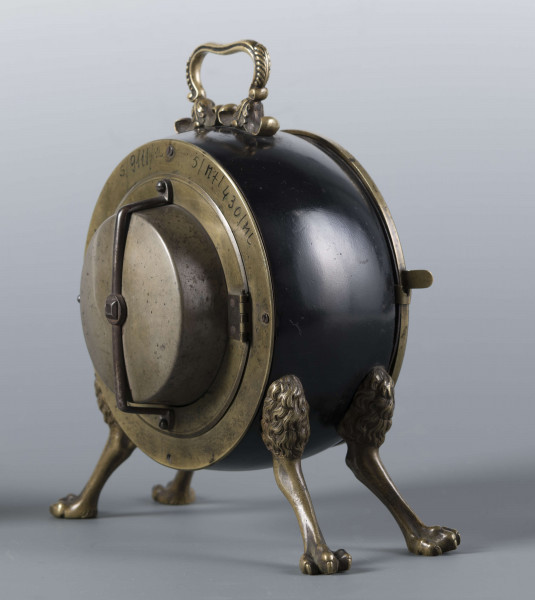 S/Mt/430/ML - Obudowa z brązu w formie bębna leżącego na czterech zwierzęcych łapach, pokrytego czarnym lakierem, z pionowym uchwytem w formie rozciągniętej profilowanej, wolutki. Tarcza zegarowa z mosiądzu, okrągła, moletowana mz malowanymi czarnymi cyframi rzymskimi godzin i oznaczeniem minut; dwie proste wskazówki; osłonieta zamykaną szybką o wypukłym profilu. Zamknięcie z tyłu w postaci okrągłych drzwiczek na zawiasie, z wmontowanym jednym dzwonkiem. Mechanizm mosiężny, o naciągu sprężynowym, z biciem godzin i kwadransów.
Na płycie wewnętrznej mechanizmu grawerowana sygnatura kursywą:
- Jacobus Staigier Lublin
